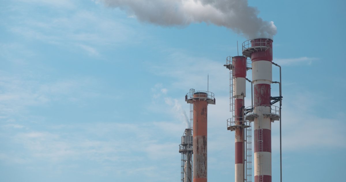 Chimeneas industriales expulsando humo blanco contra un cielo azul
