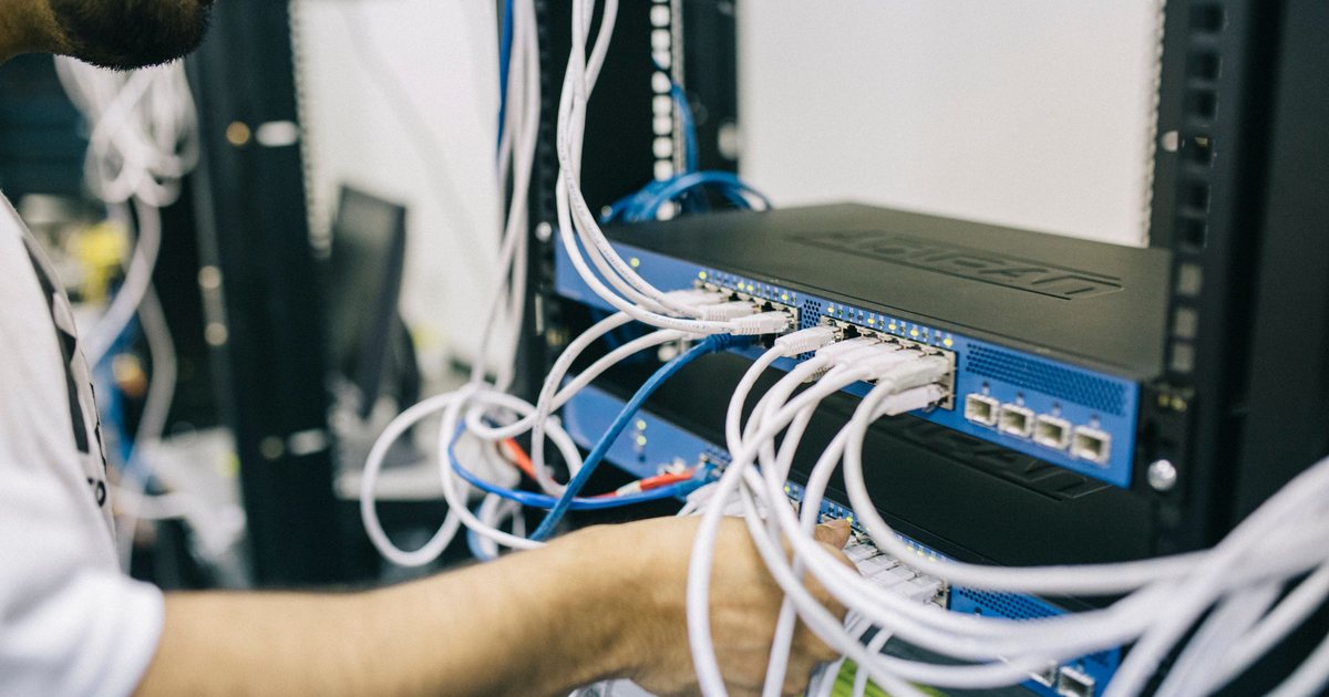 Técnico conectando cables de red en un armario de servidores
