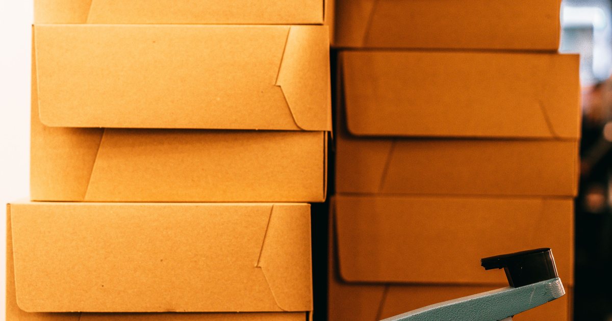 Cajas de cartón apiladas junto a una selladora en una línea de envasado
