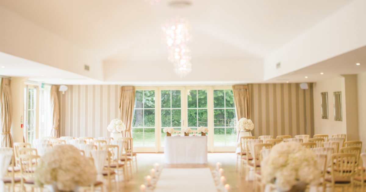 Sala de eventos de un hotel decorada en blanco, con cortinas y sillas vacías