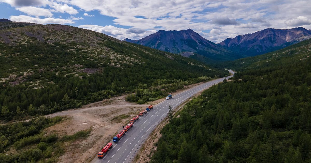 Vista aérea de una fila de camiones circulando por una carretera entre montañas