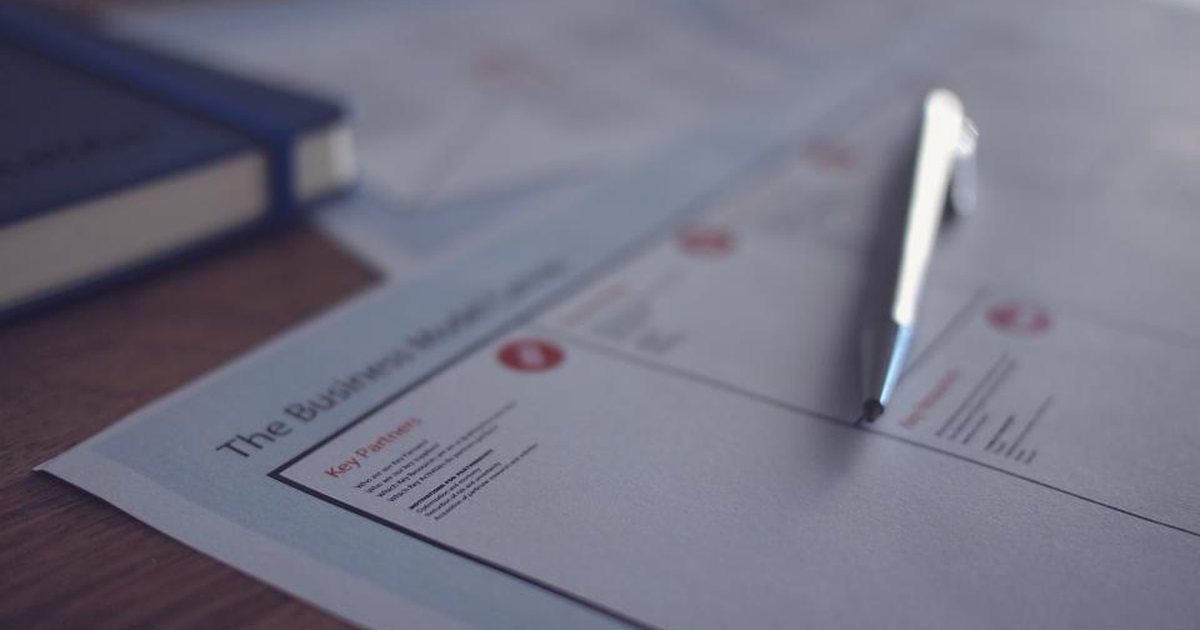 Mano sosteniendo un bolígrafo sobre un documento con un plano técnico