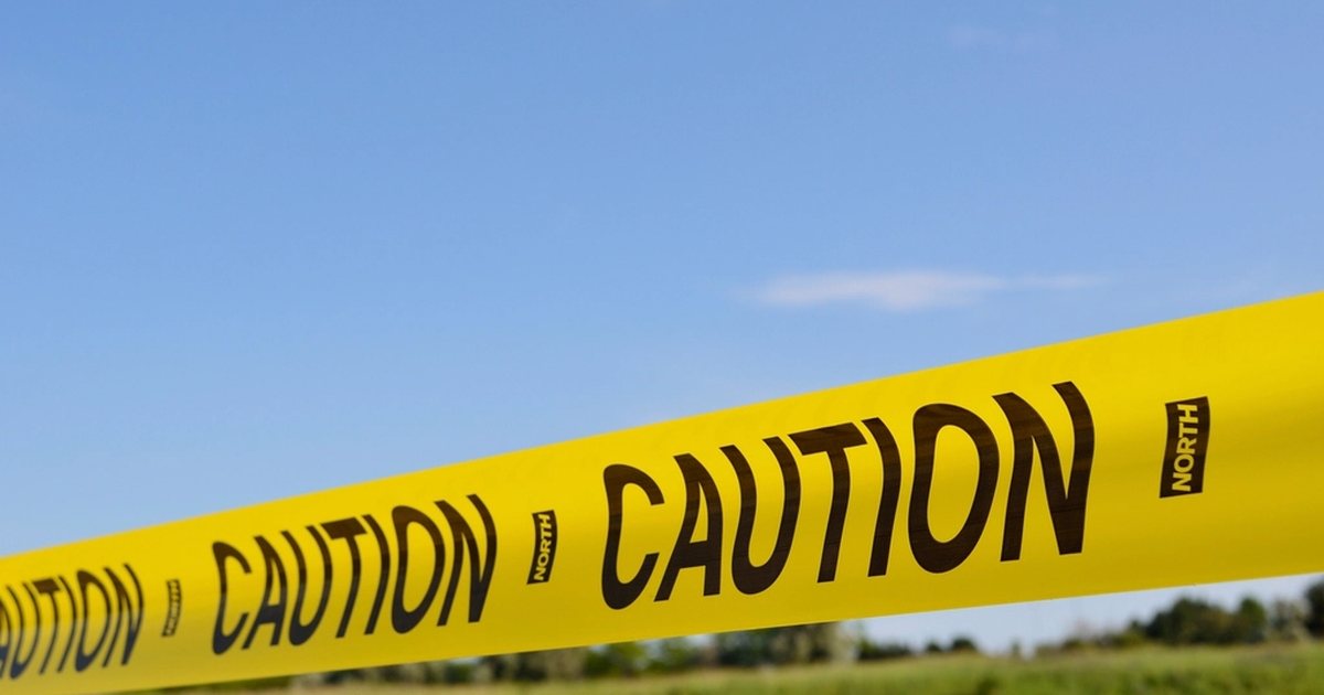 Cinta de precaución amarilla con la palabra CAUTION extendida sobre hierba