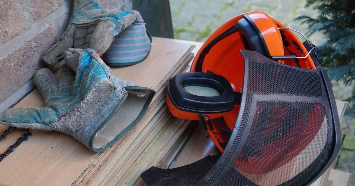 Botas de trabajo y un casco de protección rojo sobre un banco de madera