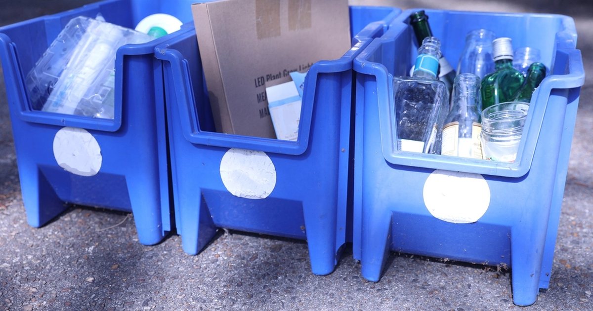 Cajas azules de reciclaje con botellas de vidrio y plástico