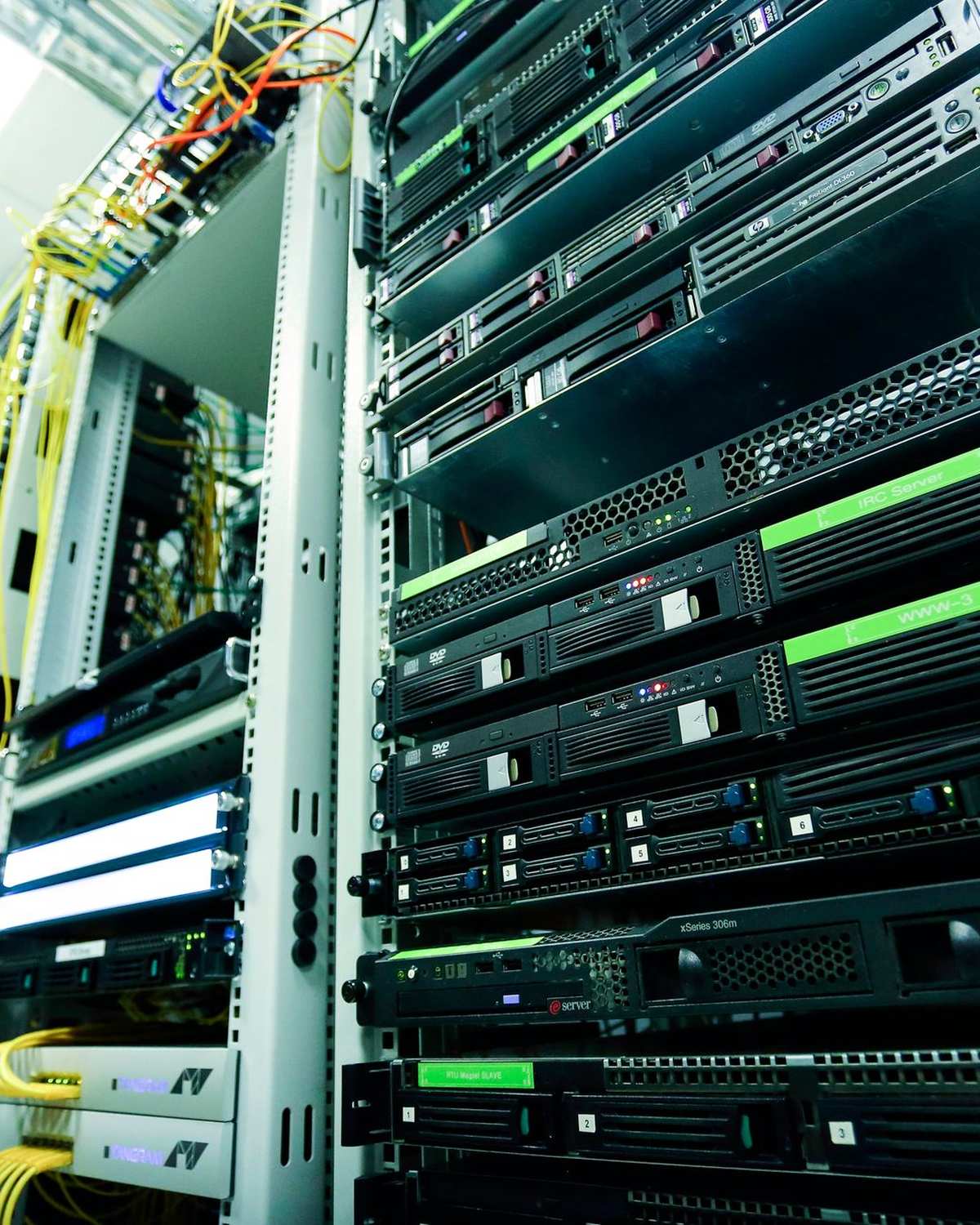 Bastidor de servidores con equipos negros, luces verdes y cables amarillos