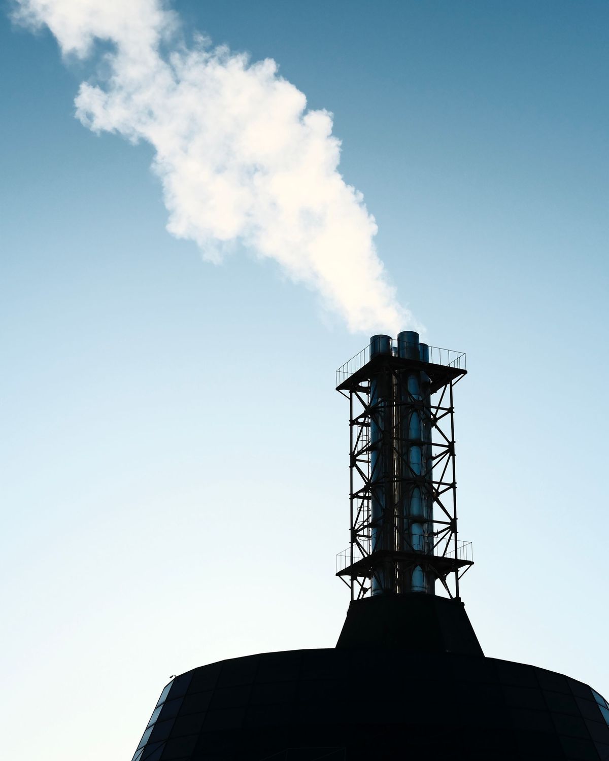 Chimenea industrial emitiendo humo blanco contra un cielo azul despejado