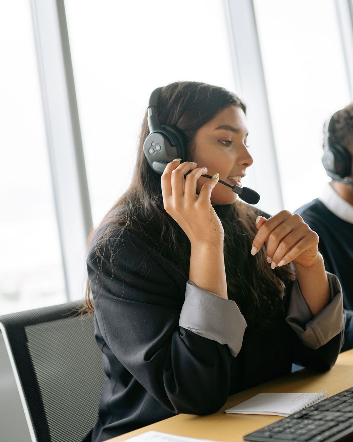 Teleoperadora con auriculares atendiendo una llamada en una oficina luminosa