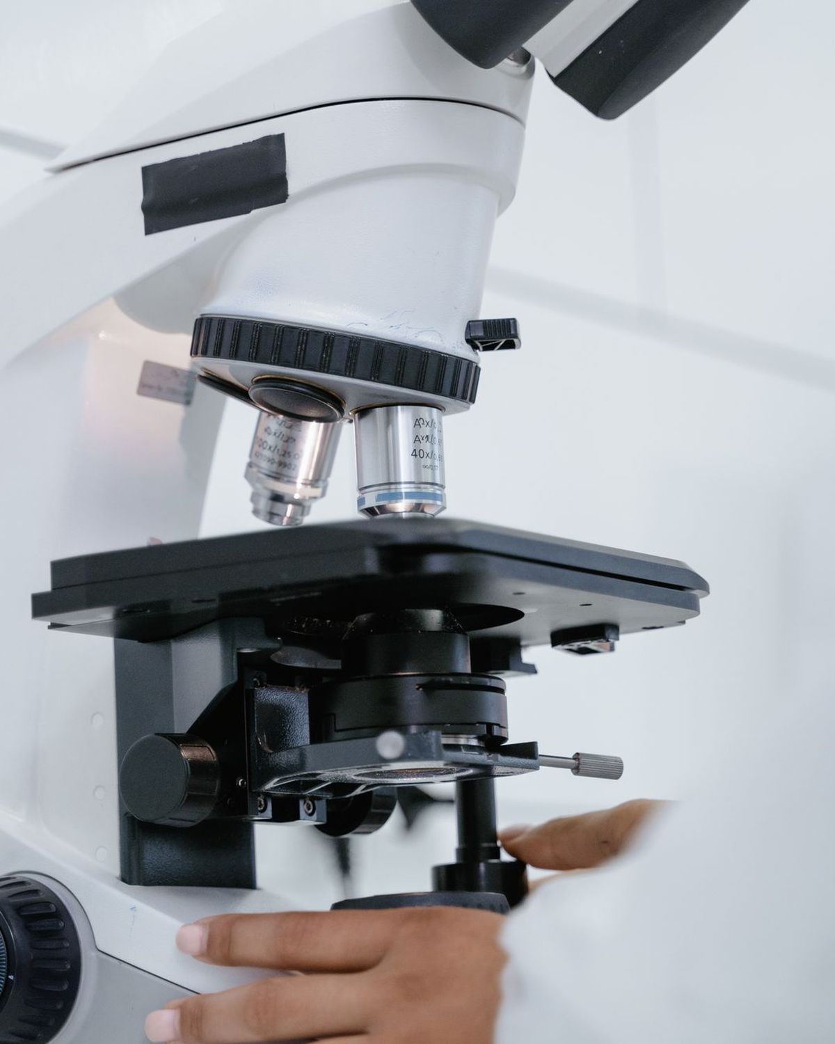 Microscopio de laboratorio blanco en primer plano con objetivos y platina