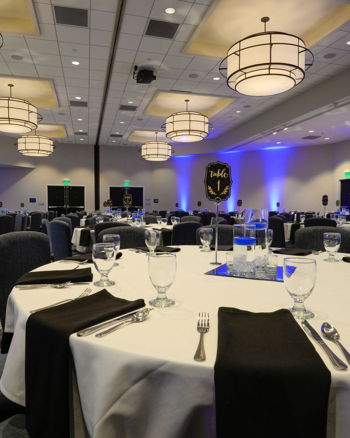 Salón de banquetes con mesas redondas preparadas para un evento y luces azules