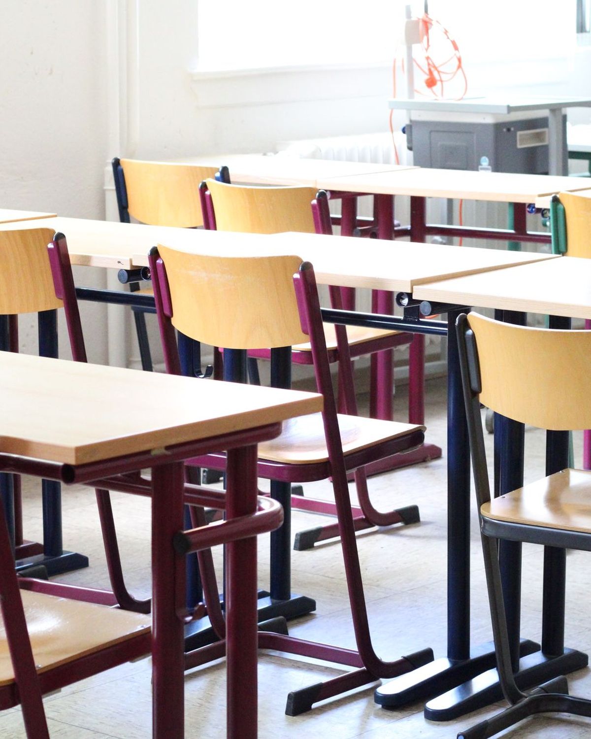 Aula luminosa con pupitres y sillas de madera preparadas para los alumnos