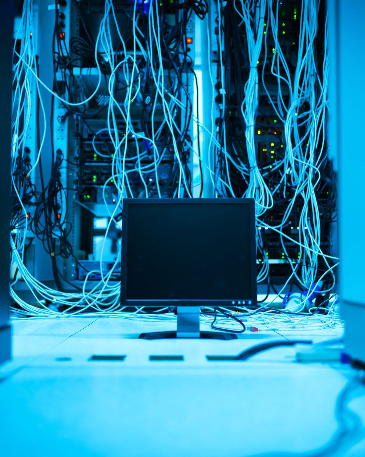 Monitor entre una maraña de cables de red iluminada en azul