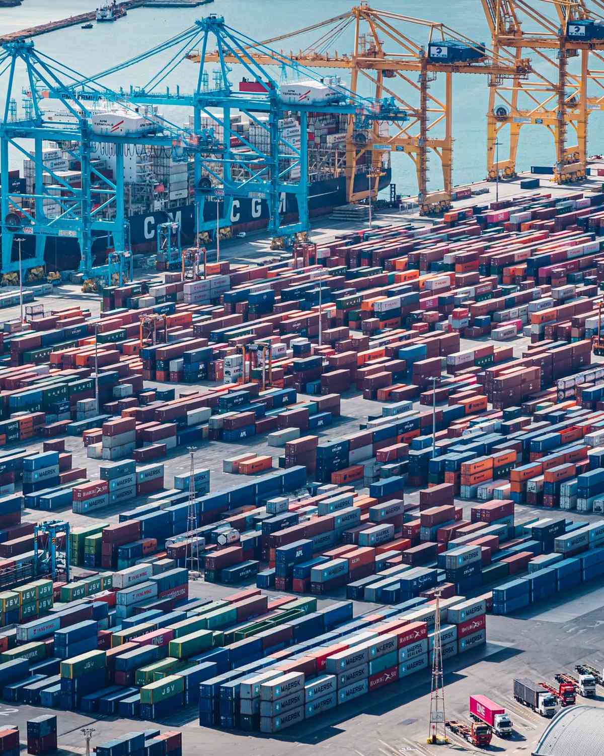 Vista aérea de contenedores apilados y grúas en una terminal portuaria
