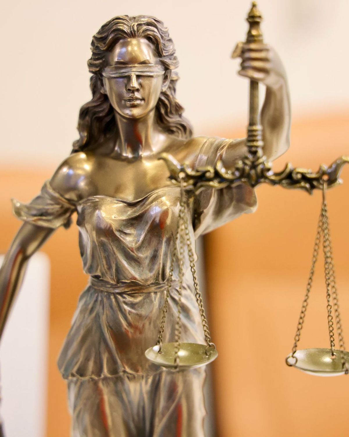 Estatua dorada de la justicia con los ojos vendados sosteniendo la balanza