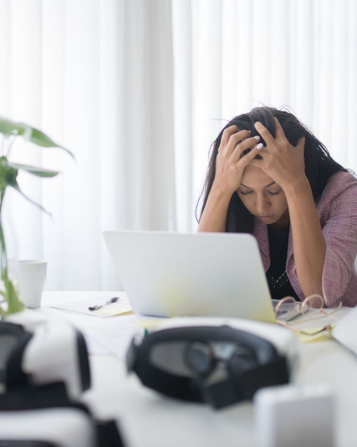 Mujer con las manos en la cabeza ante un portátil, estrés laboral